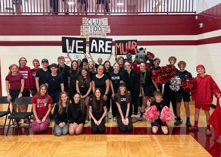 Students gather with signs that say, "We Are Muir" at the Pep Assembly during Spirit Week