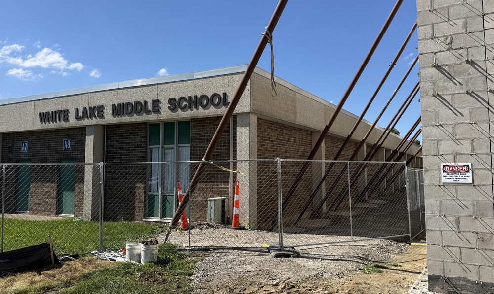 Photo of school buidling facade with construction on the right hand side. The building reads "White Lake Middle School"