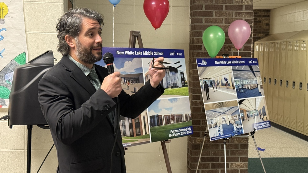 Supt. Paul Salah speaking to crowd in front of renderings for renovated middle school 