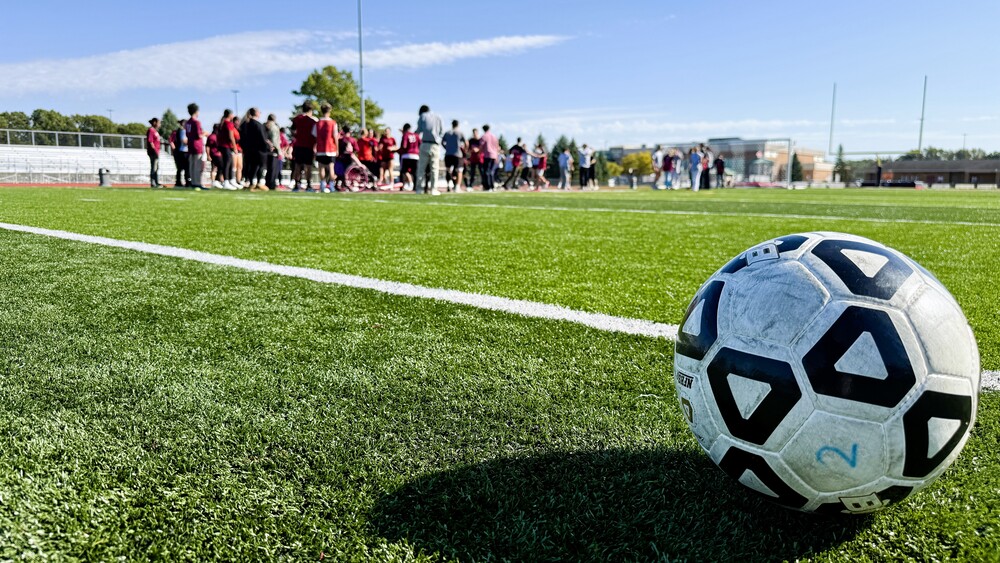 Photo of soccer player on firled with a ball in the foreground