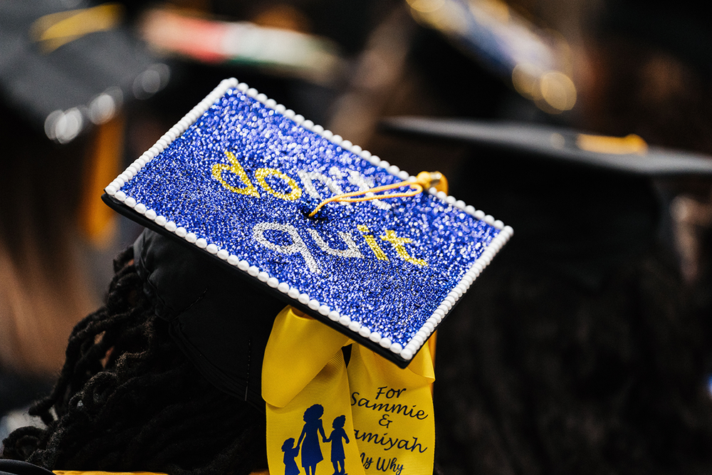 Picture of grad cap worn on a woman which states Don't Quit