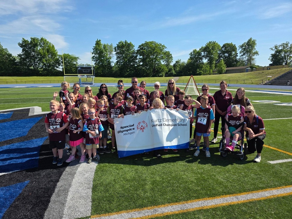 Photo of students holding a banner at the special olympics event on a football field