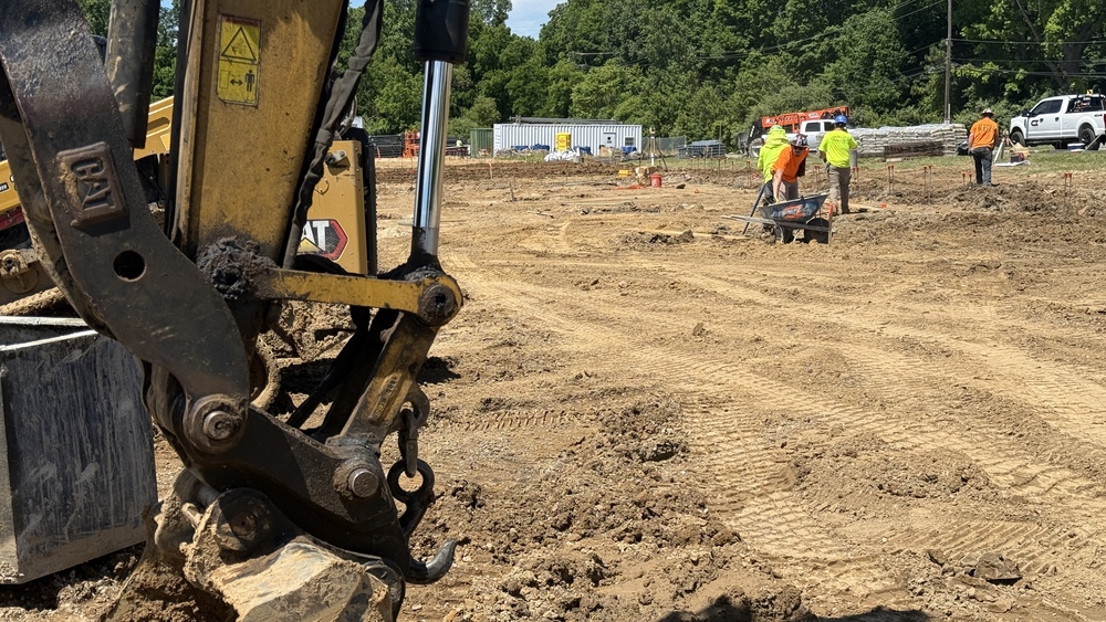 Image of men working on construction site with brown dirt and a backhoe.