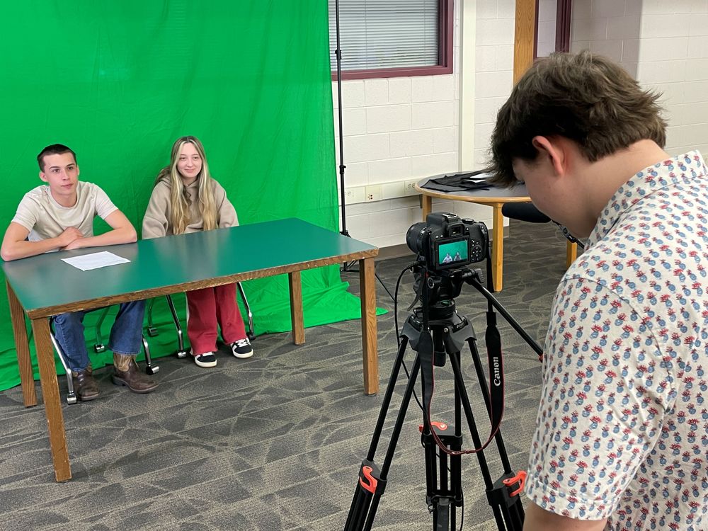 Student films news clip in front of green screen