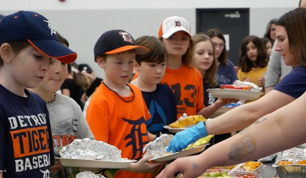 students wearing tigers gear in line to get food for opening day party