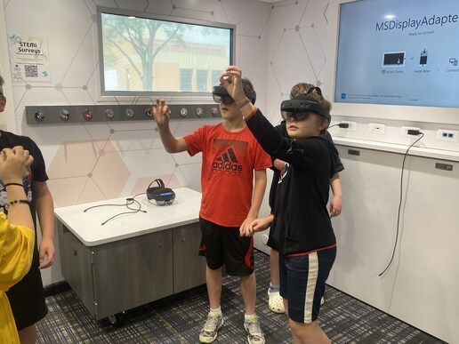 3 students standing up using virtual reality headsets 