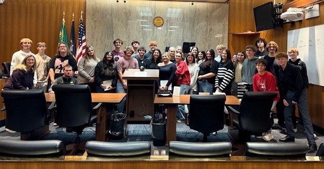 Large group of students and a judge in a court room.