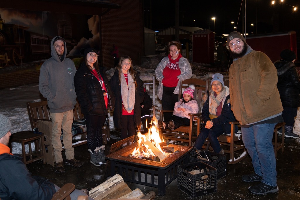 Highland Family Standing around the bonfire at the Highland Tree Lighting