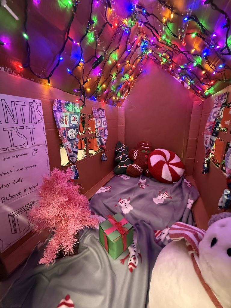 Inside kid sized gingerbread house. Filled with Christmas lights a blanket and fun holiday pillows.