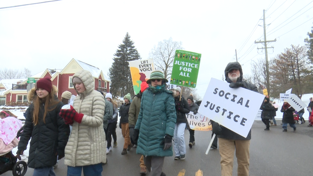 People walking in parade in Milford to honor martin luther king jr sign read 'social justice'