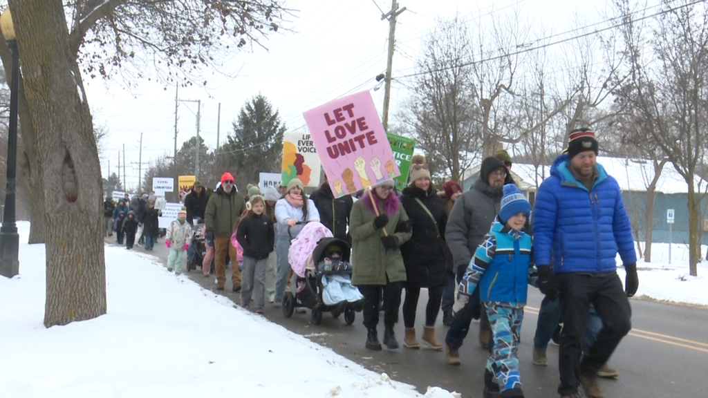 People walking in parade in Milford to honor martin luther king jr sign read 'let love unite'