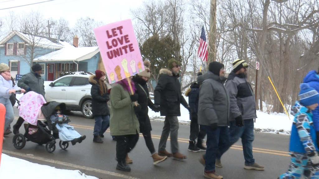 People walking in parade in Milford to honor martin luther king jr sign read 'let love unite'