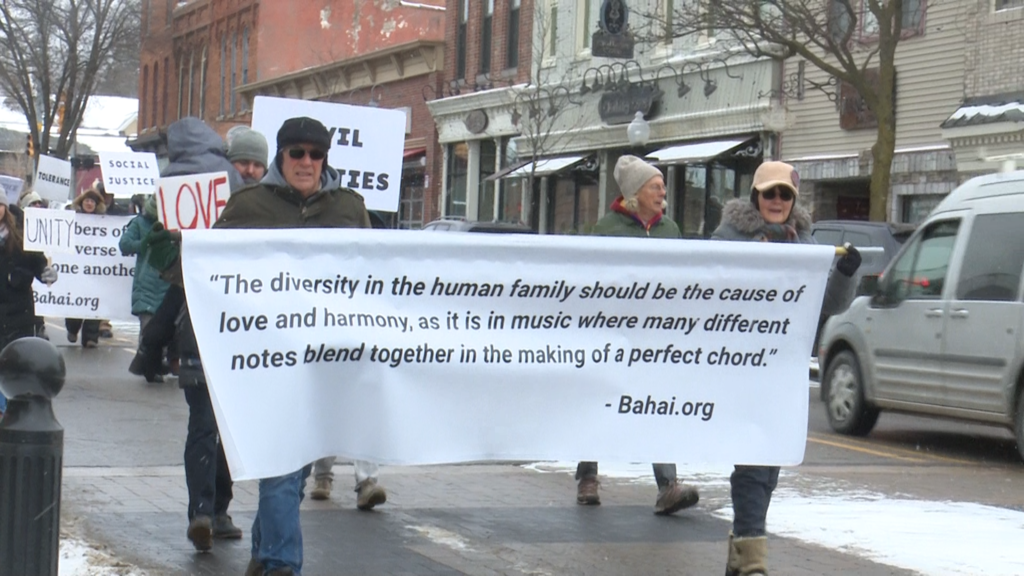 People walking in parade in Milford to honor martin luther king jr thru downtown streets