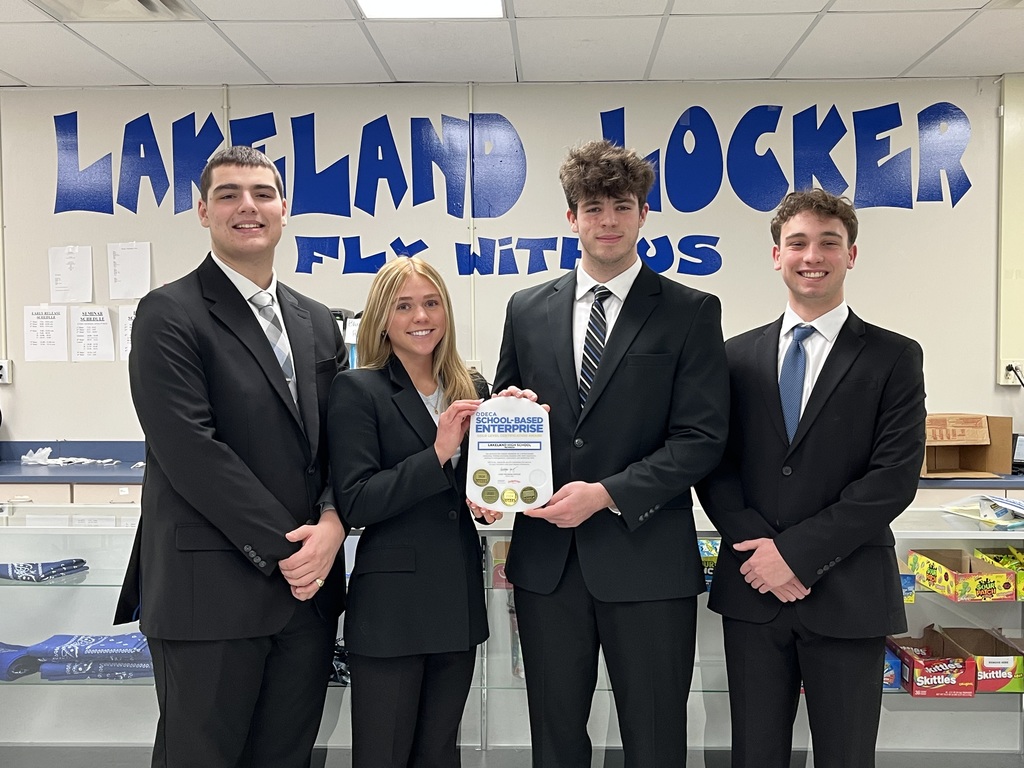 Four students dressed up holding a plaque