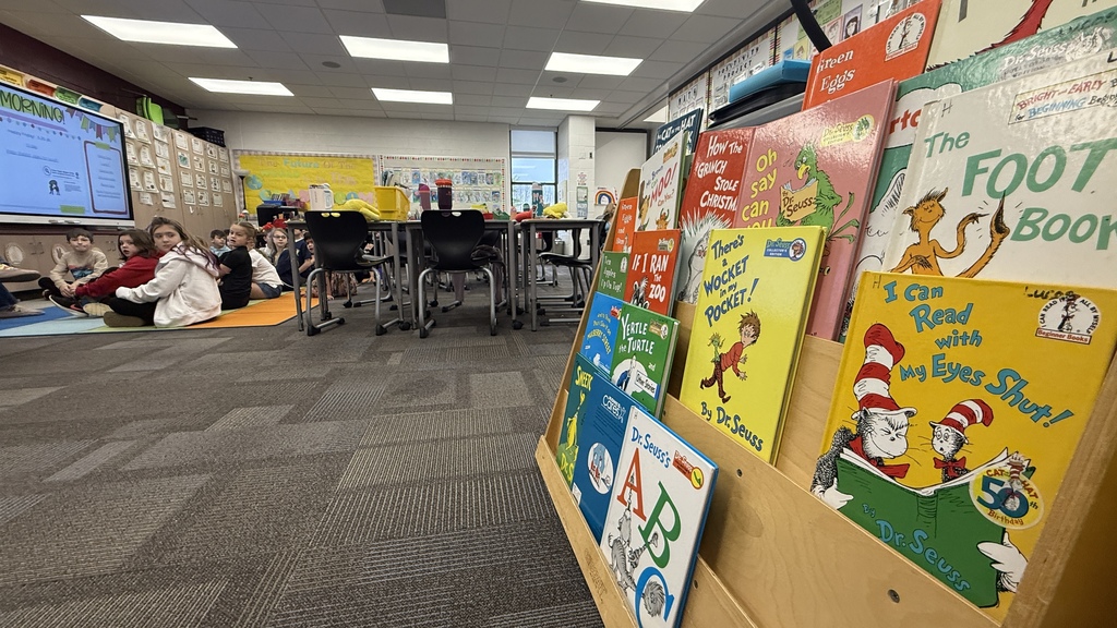 Students sitting on floor in classroom, childrens books in the foreground