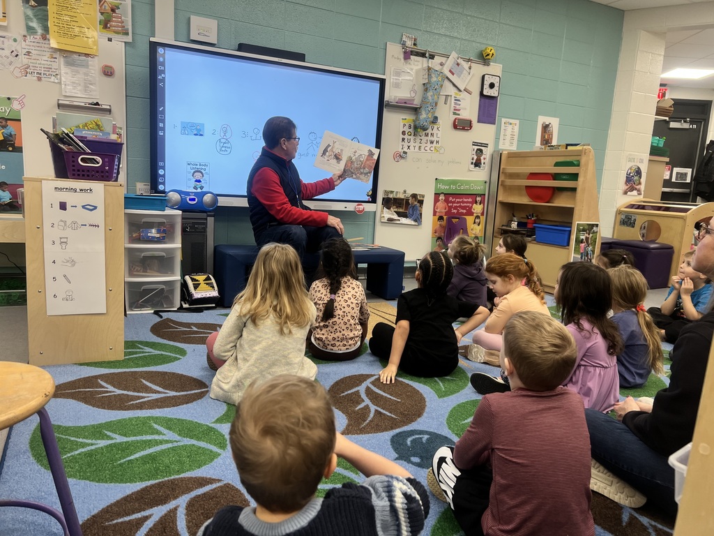 HVS Board member Tom Wiseman reading a book to kids who are sitting on the floor listening