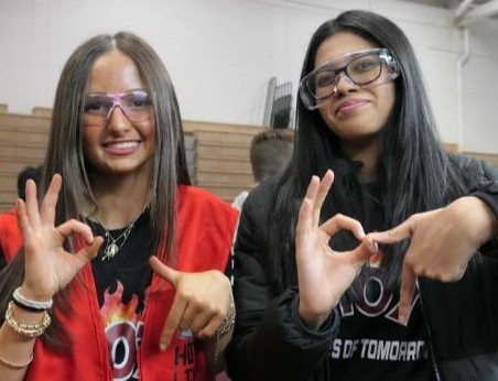 Two HVS robotics students wearing goggles and making a '6 7' hand gesture