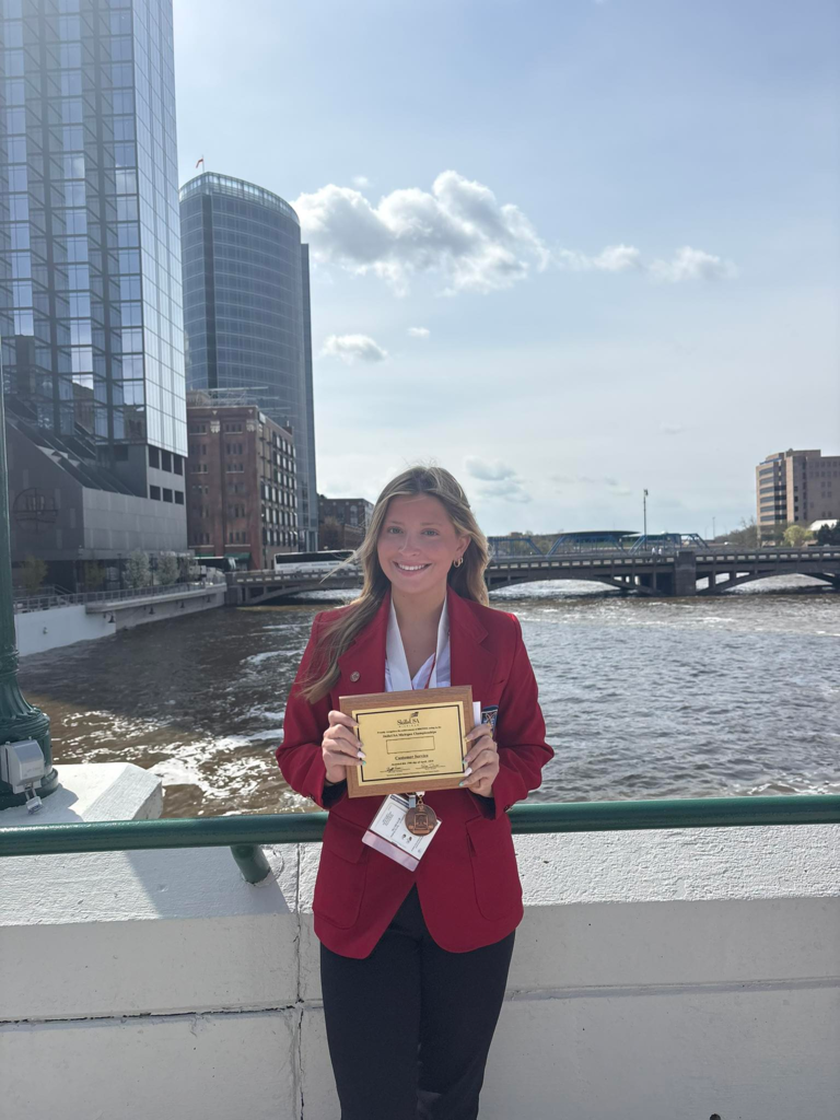 Sasha holding a plaque over looking the Grand River