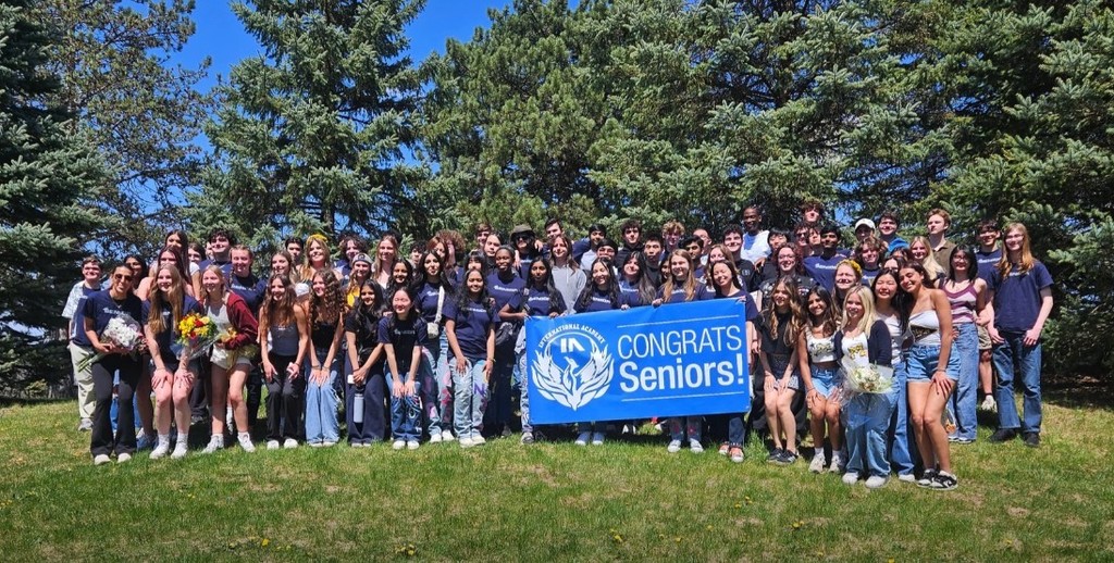 about 50 IAWest student holding a 'congrats, seniors' sign while posing for a group photo