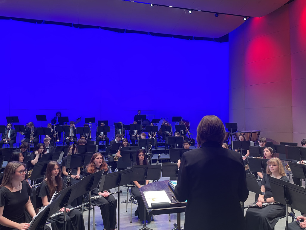 Photo of school band playing on stage being insructed