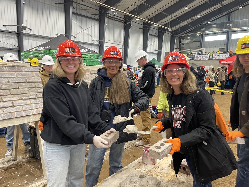 Students and staff laying brick