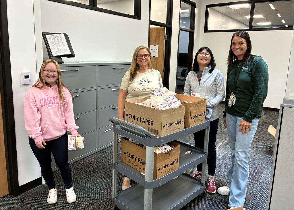 Picture of two educators and two students with a cart full of popcorn bags