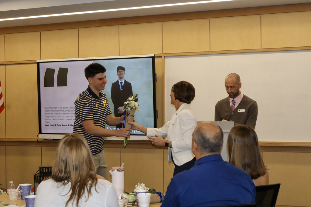 Vieu handing flowers to male student while Dr. Carlson talks.