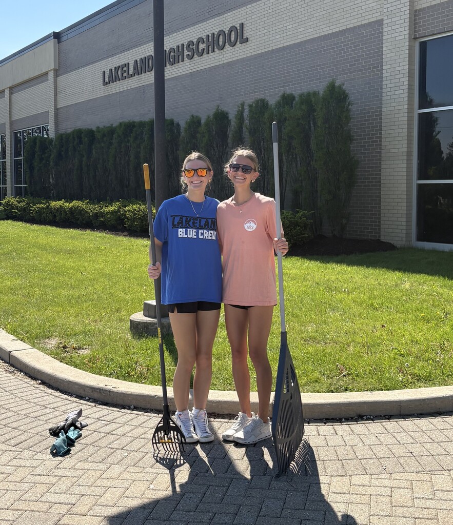students pose for photo with rakes in hand at high school