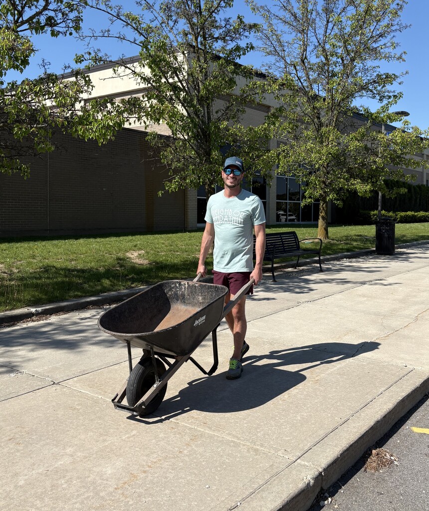 People using wheel barrels to halp clean up outside school