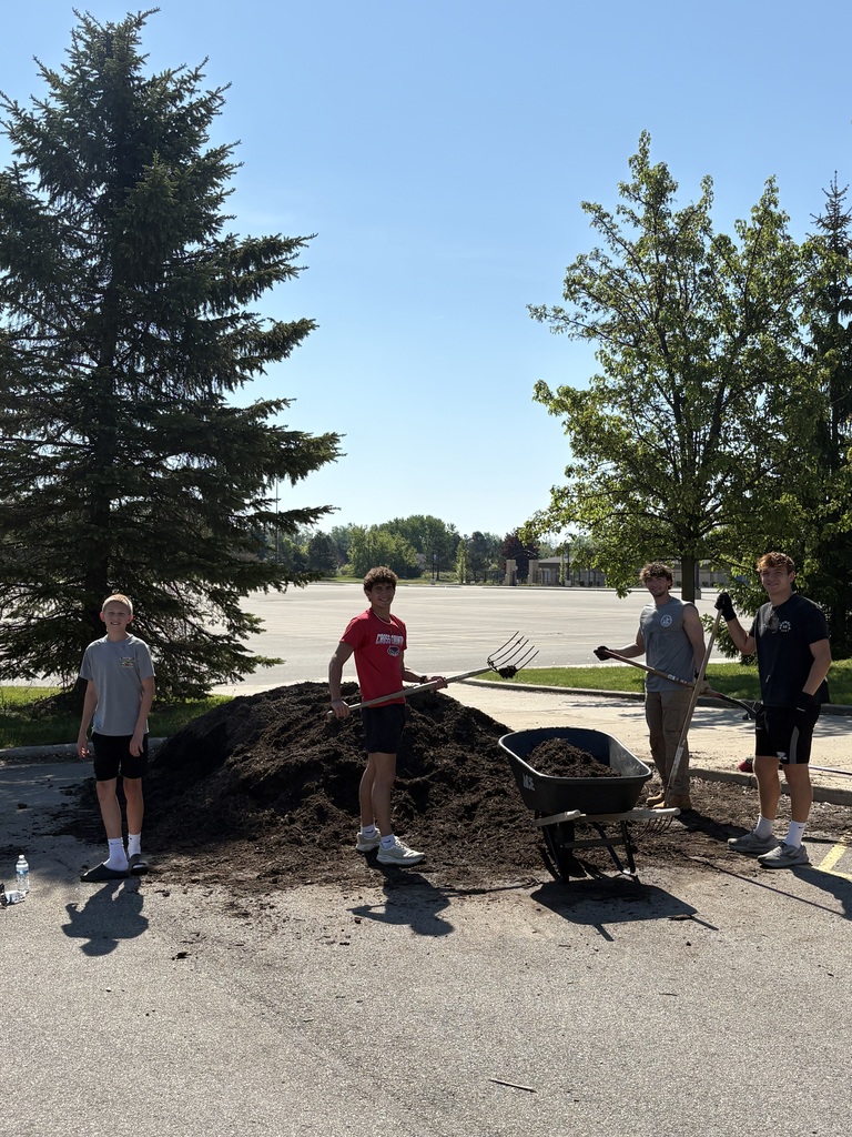 Students using wheel barrels to halp clean up outside school