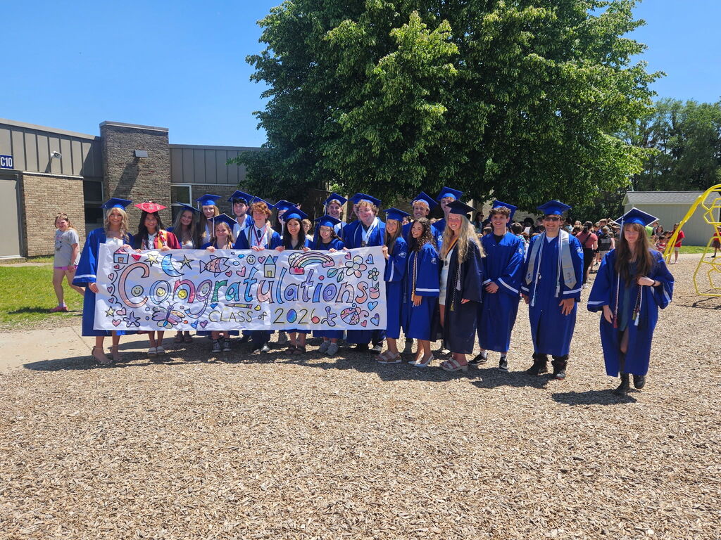 Several HVS seniors in cap & gown for graduation visiting elementary school on the playground