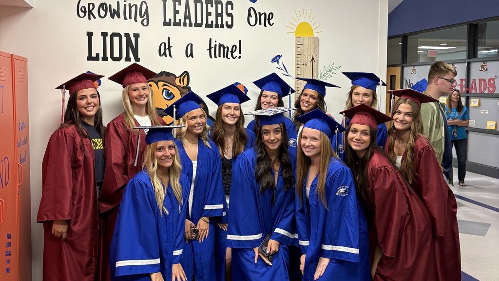 Several HVS seniors in cap & gown for graduation visiting elementary school pose for picture