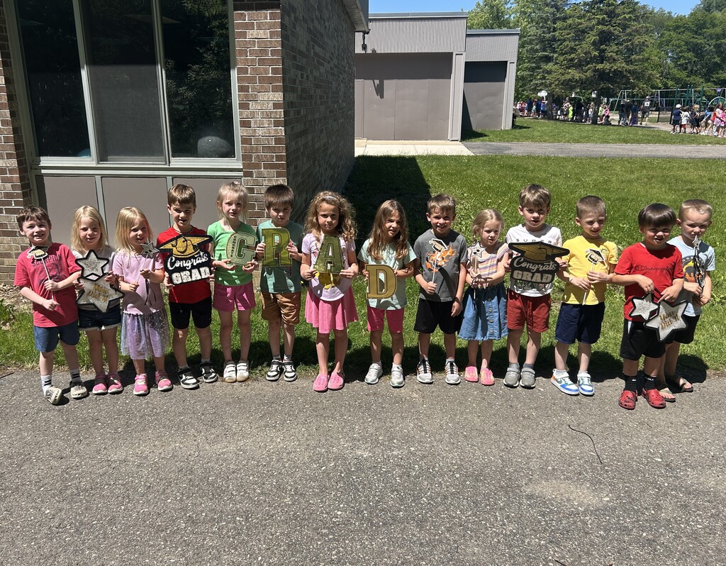 Elementary students holding up handmade signs to welcome seniors back to their school 