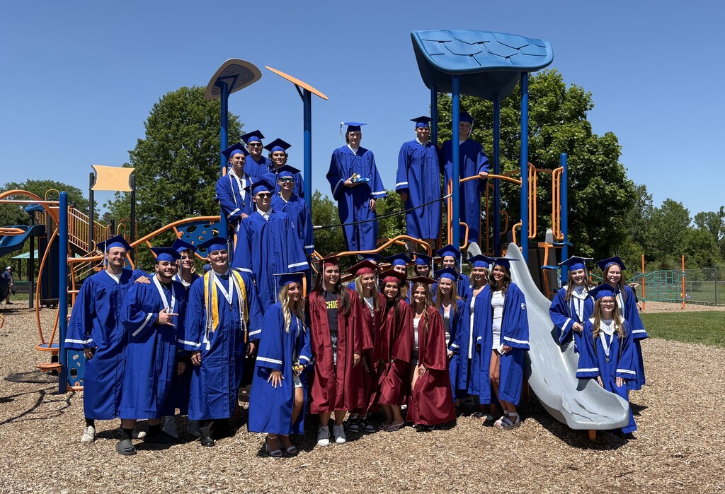 Several HVS seniors in cap & gown for graduation visiting elementary school on the playground