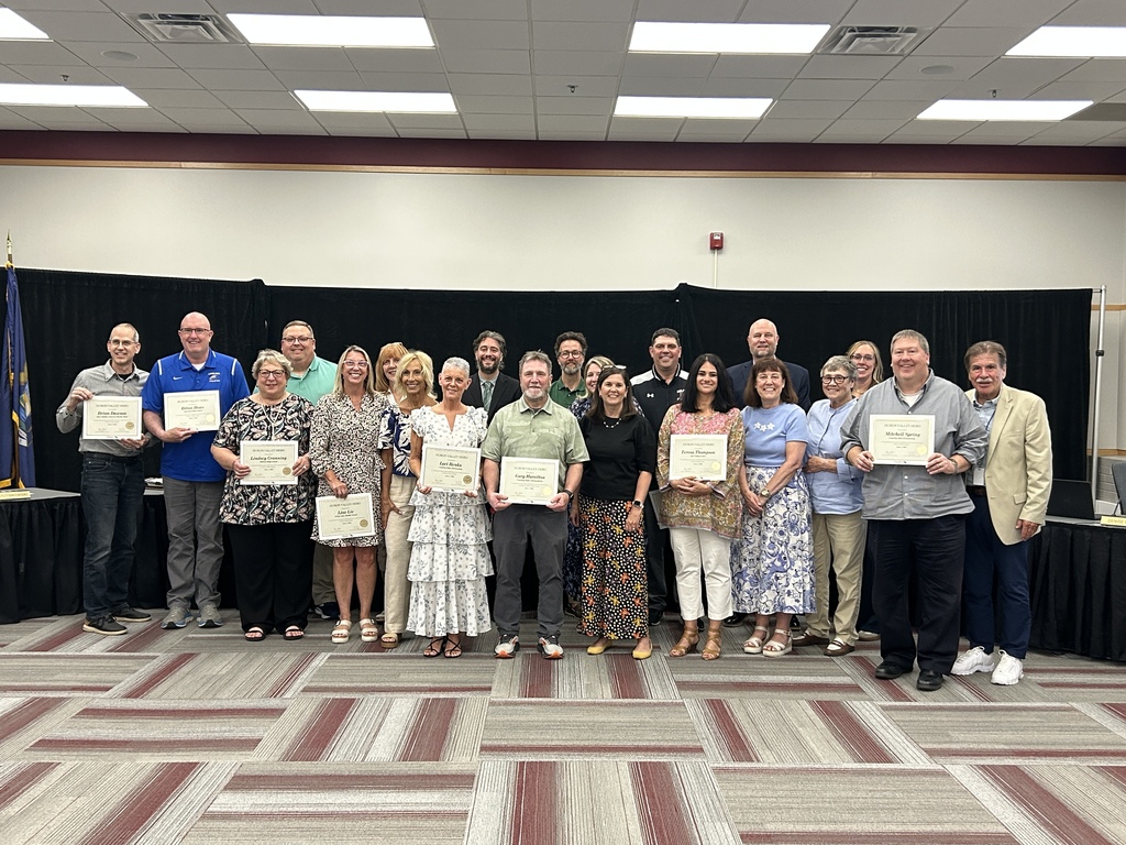 Photo of recently retired educators from Huron Valley Schools standing with certificates at school board meeting with members of board and superintendent