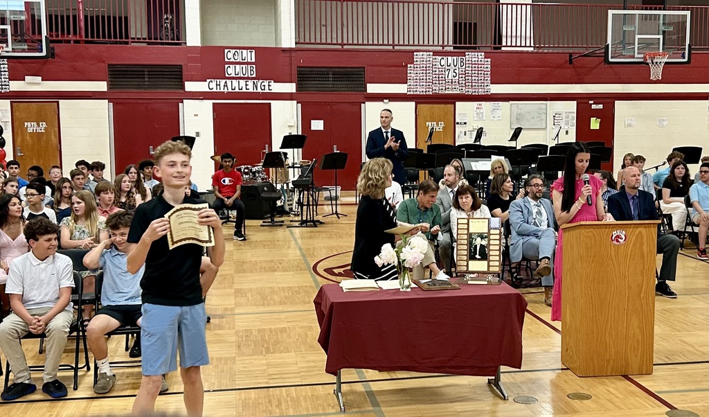 Student holding up certificate in front of school assembly for honors night