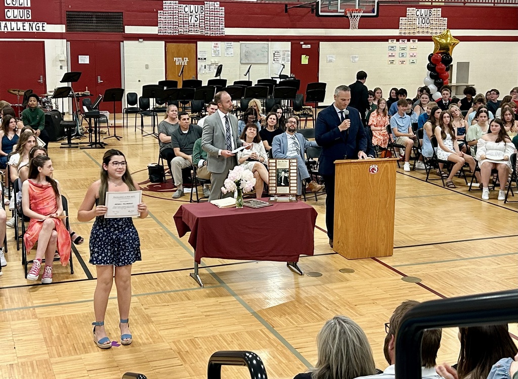 Student holding up certificate in front of school assembly for honors night