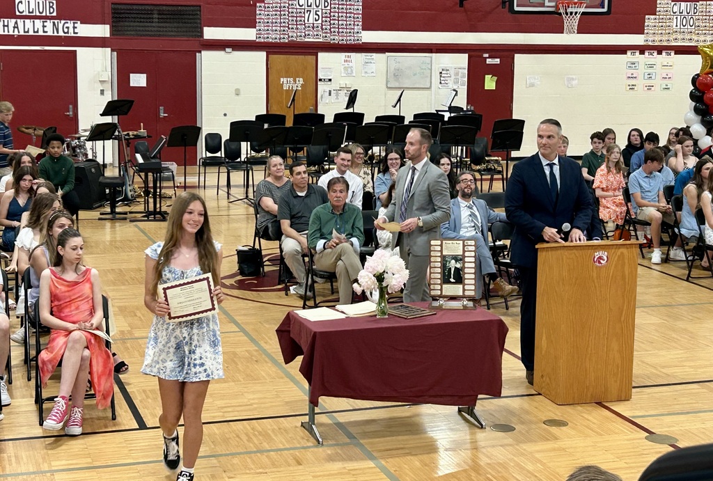 Student holding up certificate in front of school assembly for honors night