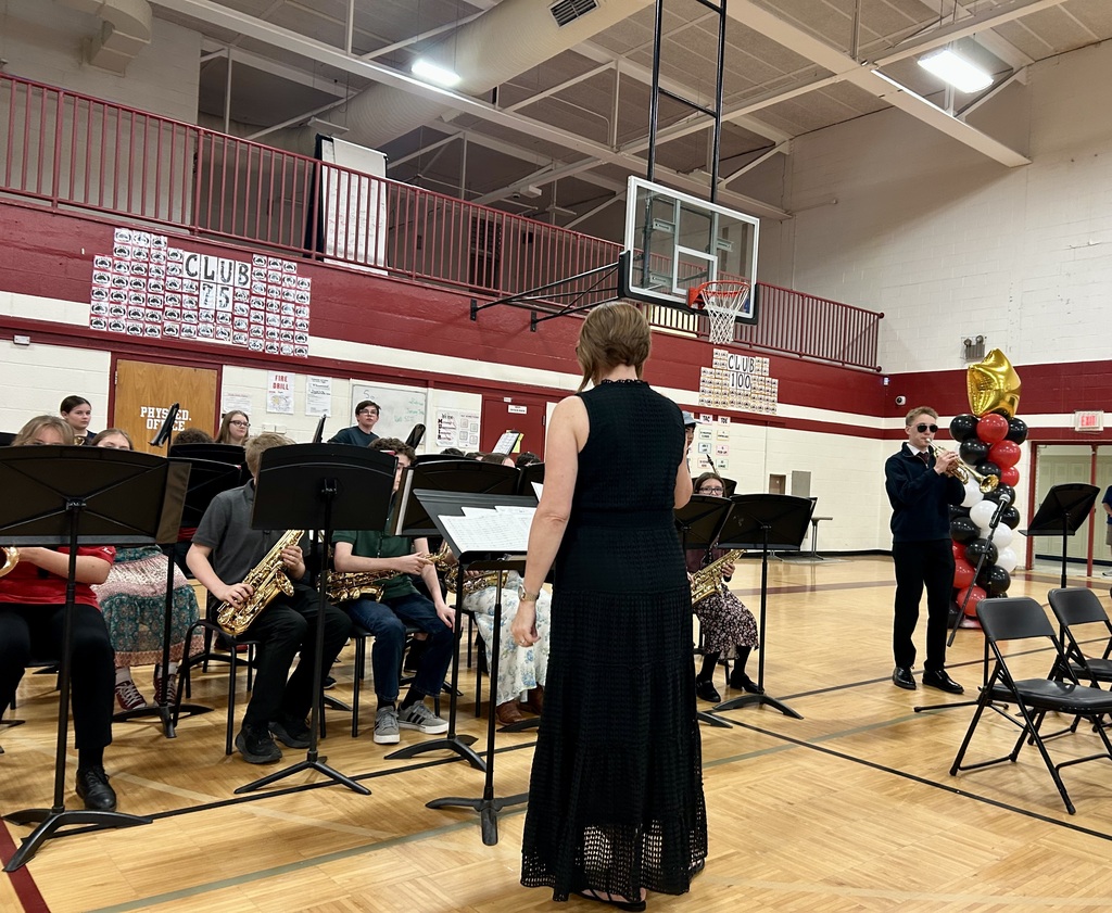 Student band on gym floor sitting and playing music
