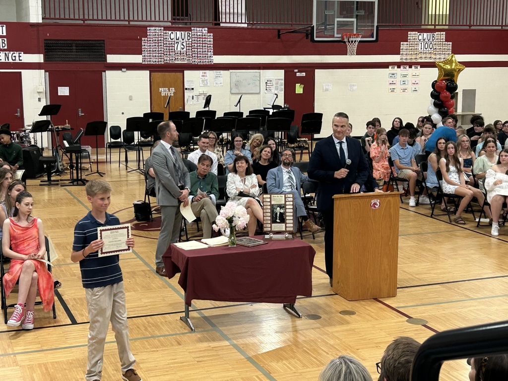 Student holding up certificate in front of school assembly for honors night