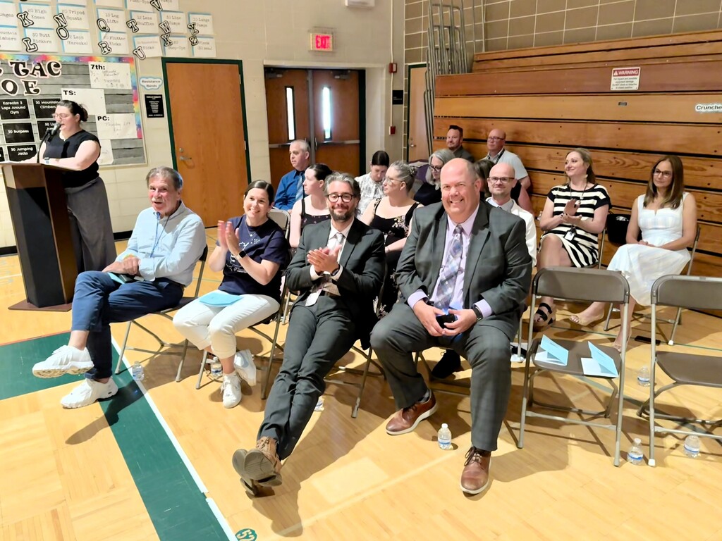 Educators and school board members applauding students as they receive awards.