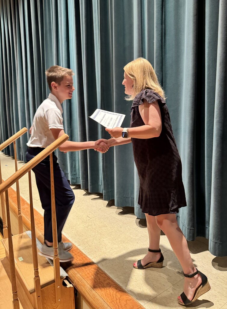 Student shaking hands with principal before receiving a certificate during a ceremony