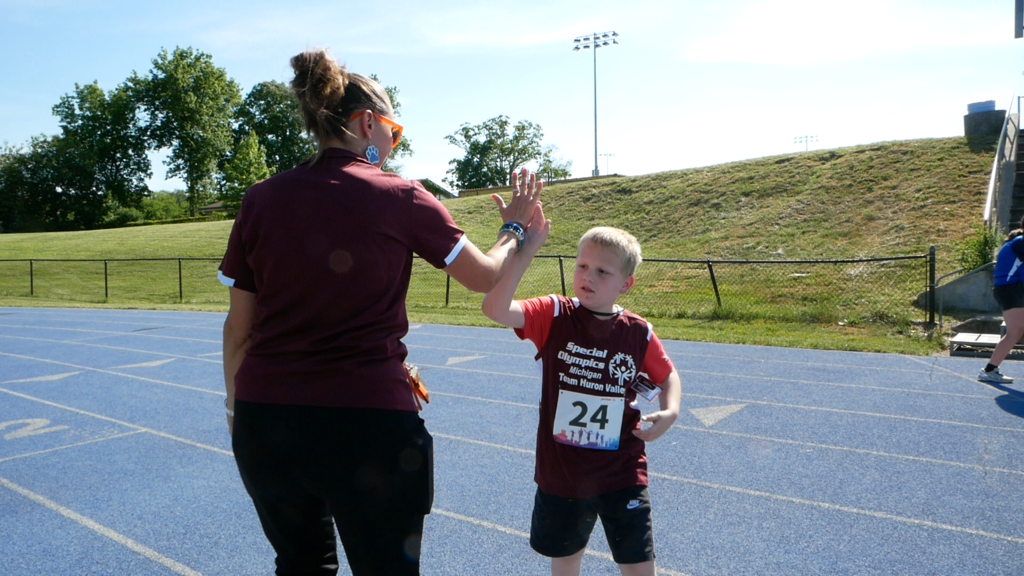 Adult high-fiving child during unified sports event