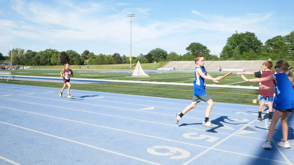Athletes handing off baton during relay race at unified sports event