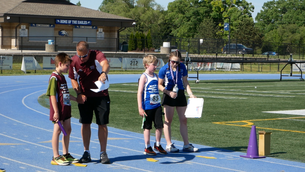 Adults instructing two unified athletes on the track before a race