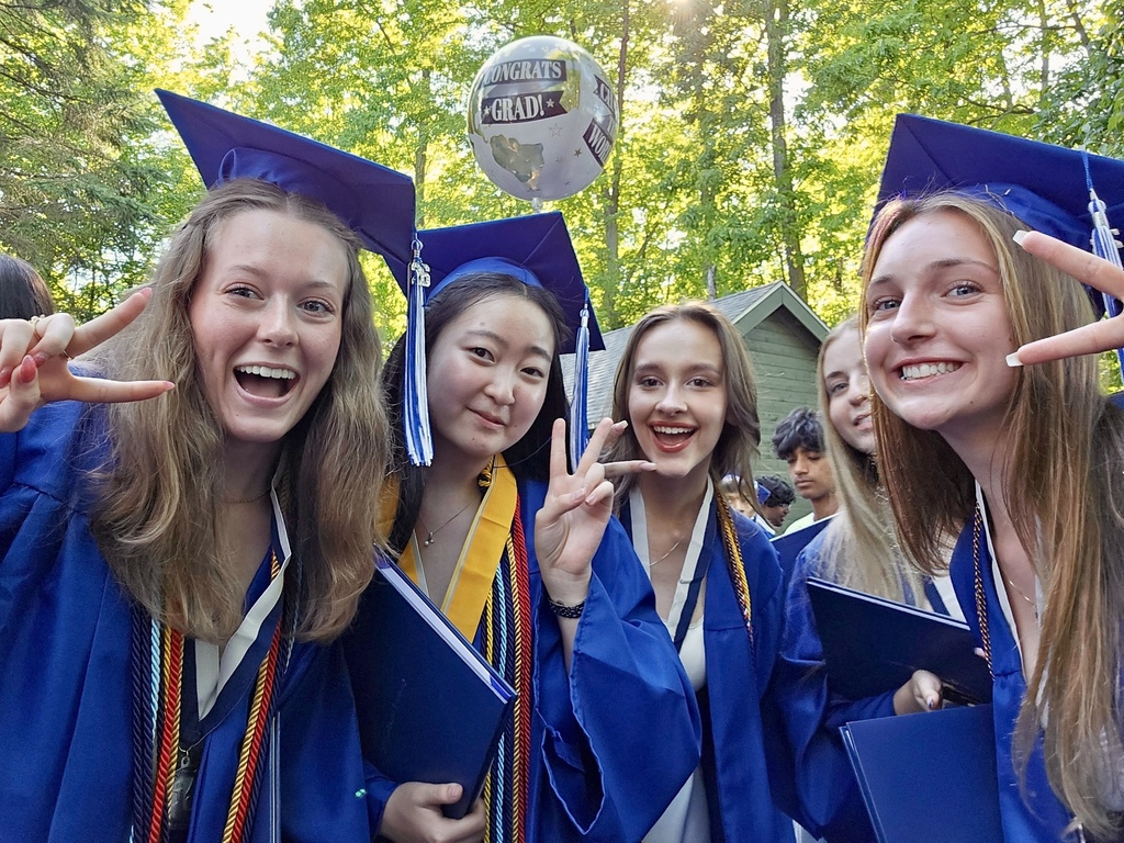 Photo of students posing for a photo at graduation day in blue caps & gowns
