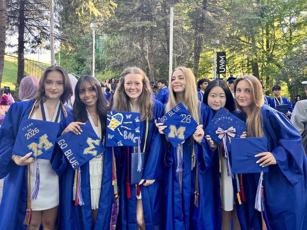 Photo of students posing for a photo at graduation day in blue caps & gowns