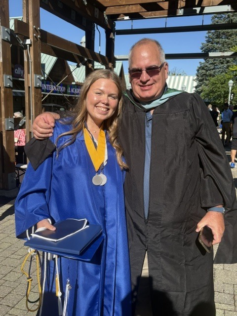 Student poses for photo with adult at graduation ceremony