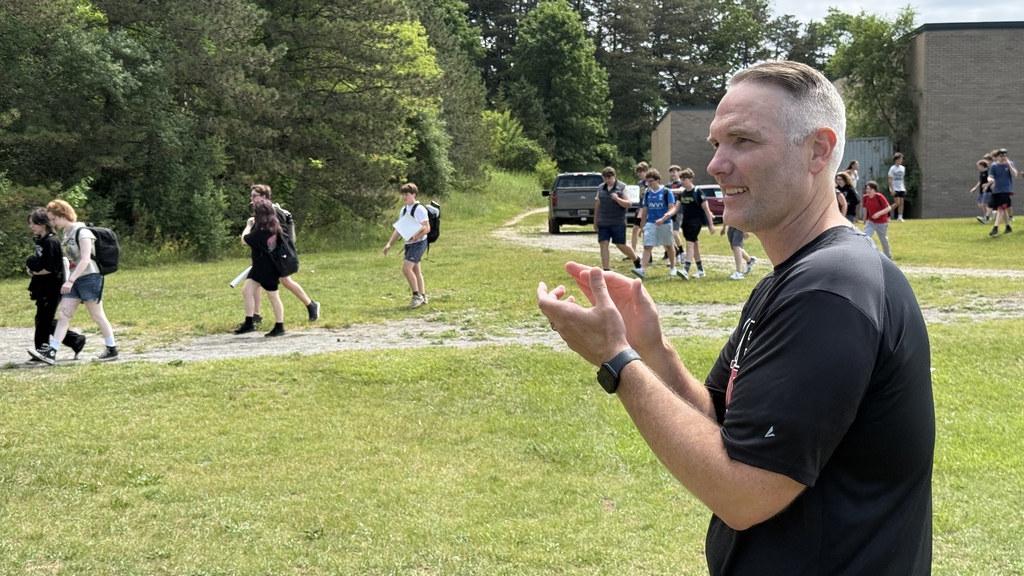 photo of steven digsby clapping out students on the last day of school.. in a field as kids walk past him