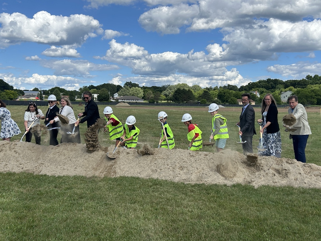 Photo of several people using shovels to dig dirt, some of them with hard hats on